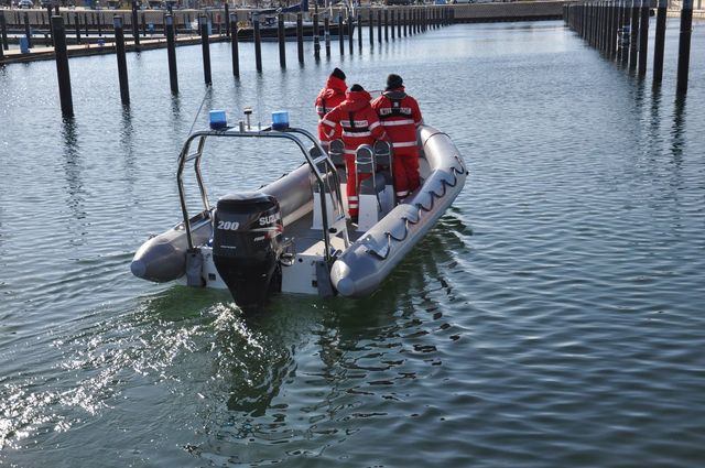 Ein Schlauchboot im Hafen besetzt mit drei Wasserwacht-Angehörigen auf dem Weg beim Auslaufen