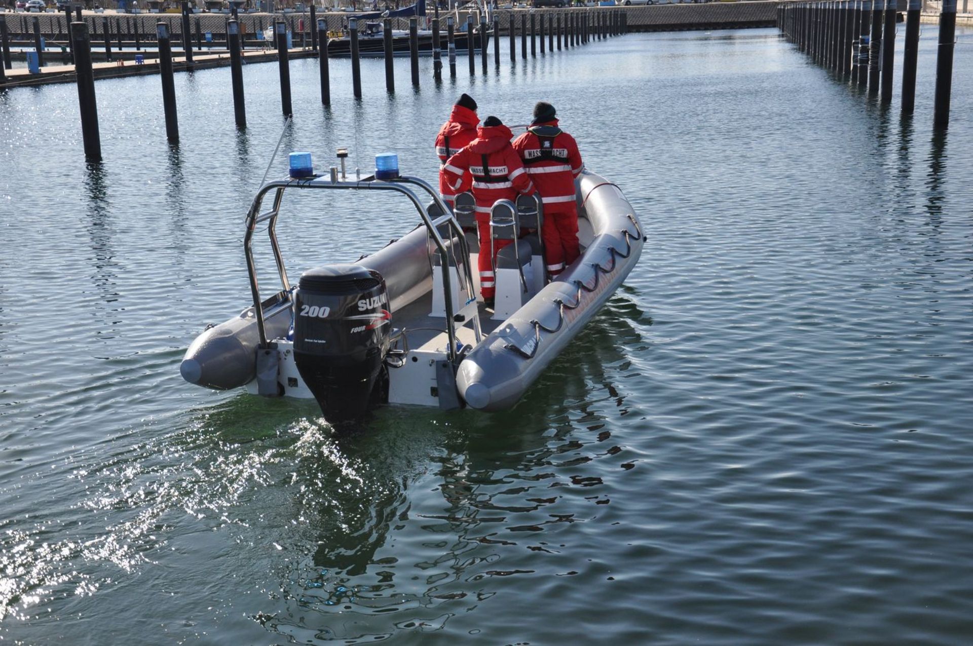 Ein Schlauchboot im Hafen besetzt mit drei Wasserwacht-Angehörigen auf dem Weg beim Auslaufen