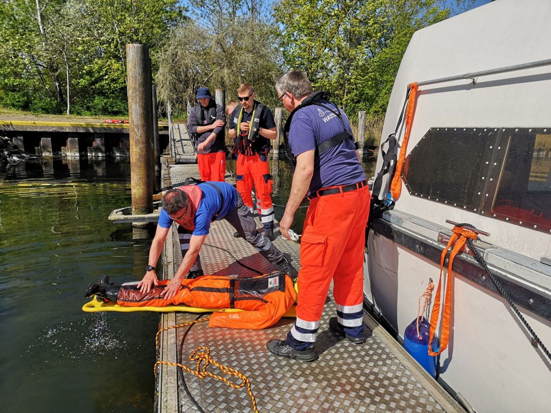 Einsatzkräfte der Wasserwacht trainieren die Übergabe einer Person am Steg