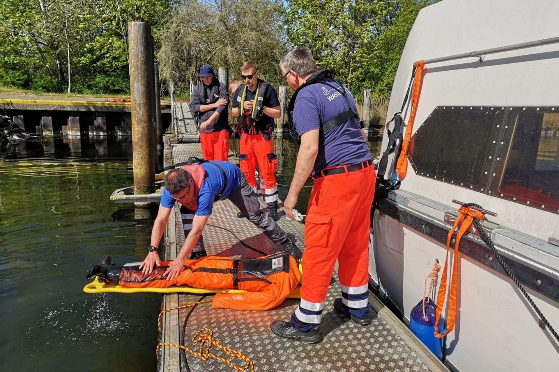 Einsatzkräfte der Wasserwacht trainieren die Übergabe einer Person am Steg