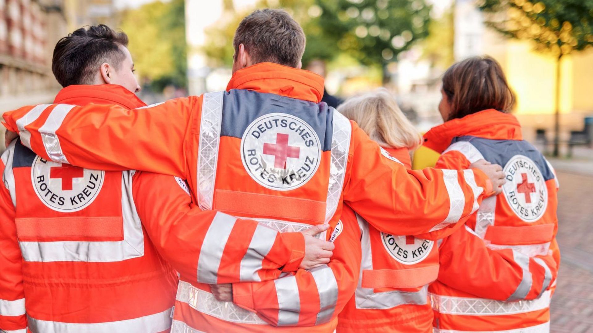Highres_DRK_Oktober_22_7921 Symbolfoto: Vier Ehrenamtliche in Einsatzbekleidung von hinten fotografiert